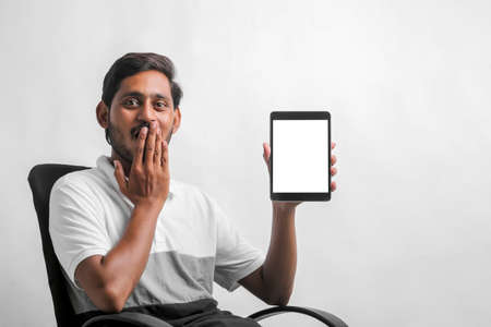 young indian man showing tablet over white background.の写真素材