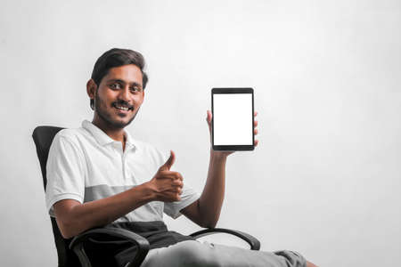 young indian man showing tablet over white background.の写真素材