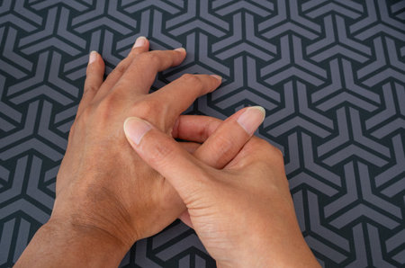 Work-related hand pain, self-massage gesture on geometric dark background. Overuse, tendon strain, office ergonomics. Medical, wellness, injury, hand therapy.の写真素材