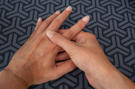 Work-related finger pain shown via targeted pressure on middle finger. Highlights musculoskeletal, tendon, nerve strain. Dark geometric background adds contrast.の写真素材