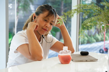 An Asian woman relaxes with her favorite music, lost in a peaceful moment of quiet joy.の写真素材