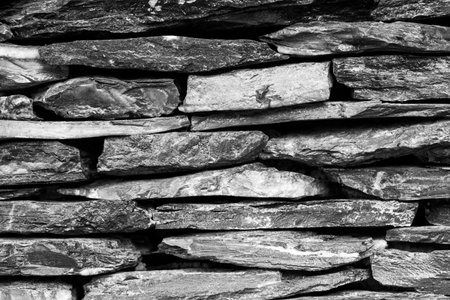 A black and white photograph background of  stone wall. Part of stone wall for background or texture.の写真素材