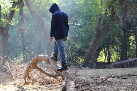 Man standing on a broken tree in the forest. The concept of destruction of nature.
