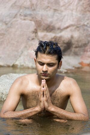Man having yoga in water between stonesの写真素材