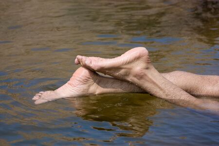 Feet of a man in the blue water of river の写真素材