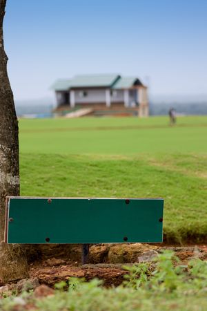 Green  Signboard on the grassland having a house の写真素材