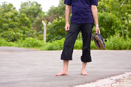 Person having walk on road taking their sandals in hands
