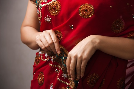woman wearing  beautifully embroidered red sari holding with hands 