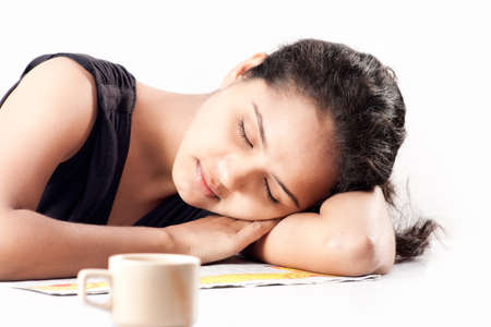 Indian girl sleeping at desk having coffeeの写真素材