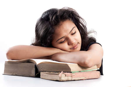 Young indian girl leaned over pile of books, isolated on whiteの写真素材
