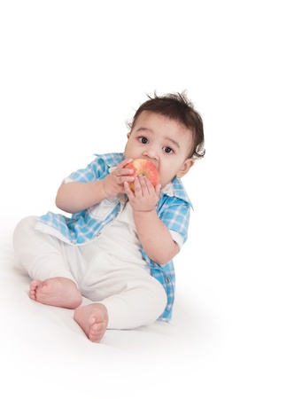Adorable Indian baby eating apple over white backgroundの写真素材