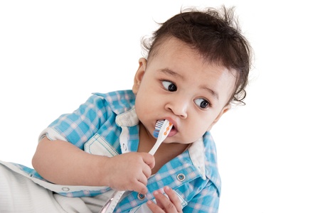 Adorable Indian baby brushing teeth over white backgroundの写真素材