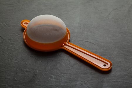 Colored plastic sieve over black backgroundの写真素材