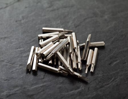 Closeup of stainless steel bits of screwdriver over black background