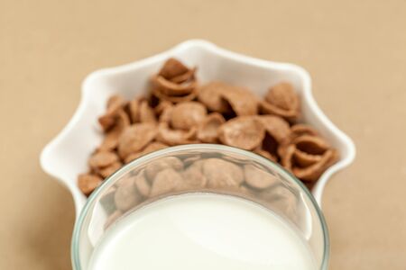 Chocolate cornflakes in white bowl and milk  glass in sepia backgroundの写真素材