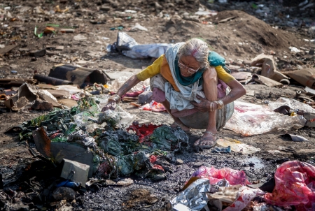Pollution and poverty   Indian old female sitting  for warmup  herself near fire  in  garbage,の写真素材