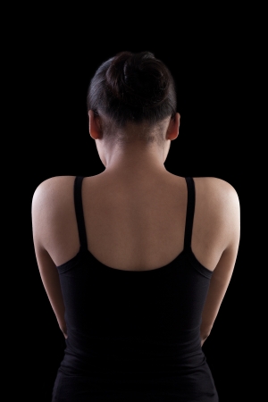 Back side of an asian woman in black dress on black backgroundの写真素材