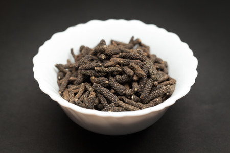 Organic Long pepper Dried Fruit Piper longum in white ceramic bowl on dark background.の写真素材