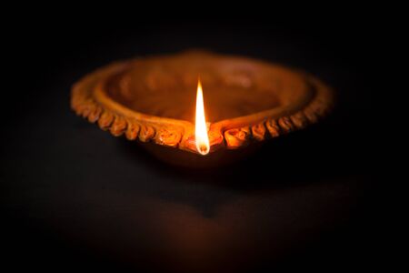 A beautiful Handmade Designer Clay Lamp with burning wick against the dark background.の写真素材