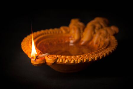 A beautiful Handmade Designer Clay Lamp with burning wick against the dark background.の写真素材