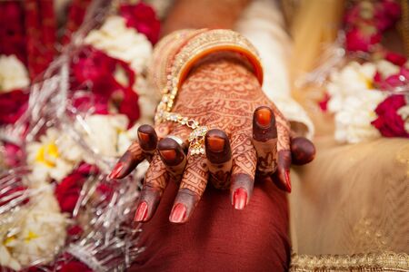 Beautiful female hand of an Indian bride, holding groom's hand during a typical Hindu wedding ceremony.の写真素材