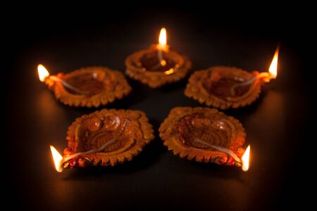 Five beautiful Handmade Designer Clay Lamps with burning wick against the dark background.の写真素材