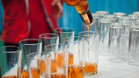 Bar tender is pouring whiskey into glasses in Punjabi wedding. Liquor Party theme.