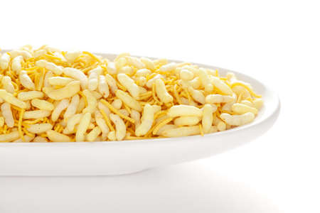 Crunchy Lemon Bhel in a white ceramic oval bowl made with Puffed Rice small besan sev. Pile of...