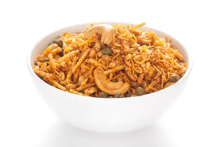 Hot spicy Kashmiri Mixture (Namkeen) snacks in a white ceramic bowl made with dry fruits, peanuts,...