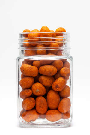 Crunchy Peanut in glass jar, made with bean coated peanuts. Pile of Indian spicy snacks (Namkeen),...