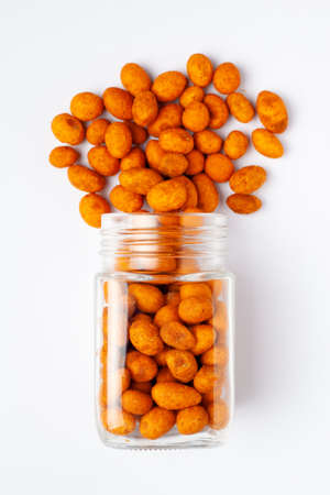 Crunchy Peanut spilled and in a glass jar, made with besan coated peanuts. Indian spicy snacks...