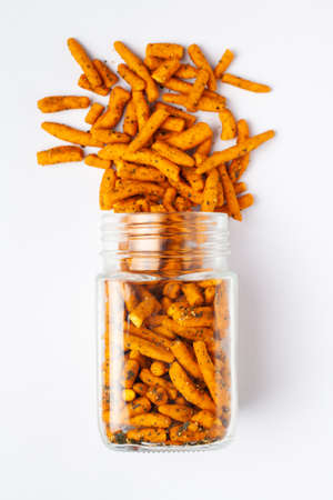 Spicy Chutney Sev spilled out and in a glass jar, made with Chickpea flour and red chili. Indian...
