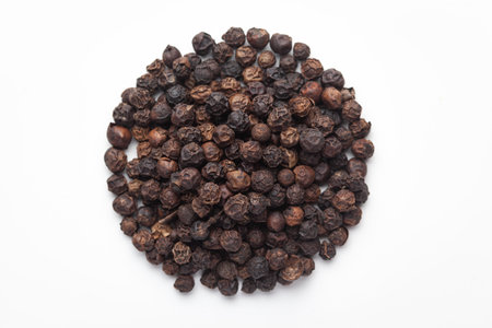 Macro close-up of Organic Black pepper (Piper nigrum) on white background. Pile of Indian Aromatic...
