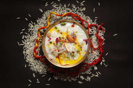 Close-up of Creamy rice Kheer(khir) Garnished with saffron and dry fruits for pooja (spiritually celebration). Indian delicious dessert. Served in a ceramic black bowl. Top View on black background.の写真素材