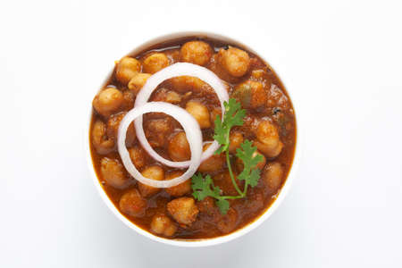 Chickpeas masala (Spicy chola or chhole curry)  garnished with fresh green coriander and ingredients. Served in a ceramic bowl. A Classic Indian typical Panjabi street food.  In white backgroundの写真素材
