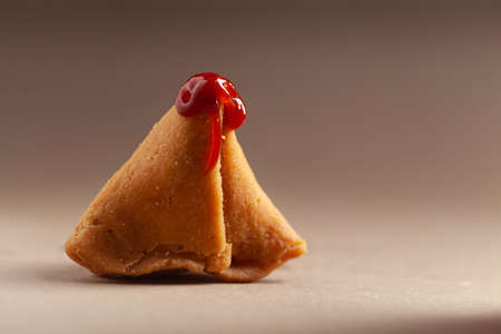 Close-up of freshly baked spicy and sweet samosa filled with dry fruits spicy dry chutney traditionally authentic Rajisthani with tomato ketchup.の写真素材