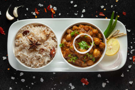 Chickpeas masala (Spicy chola or chhole curry) and Pulav (Rice) garnished with fresh green coriander and ingredients. Served in a ceramic bowl. An Classic Indian typical Panjabi street foodの写真素材