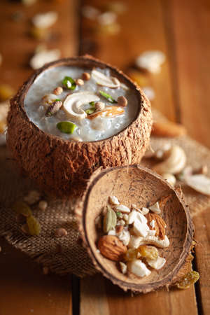 Close-up of Creamy Sabudana Kheer Garnished with dry fruits. Indian delicious dessert. Served in the coconut shell. Front view on wooden background.の写真素材