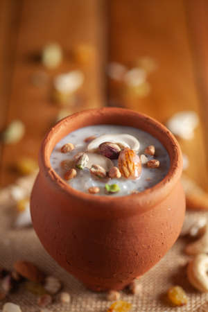 Close-up of Creamy Sabudana Kheer Garnished with dry fruits. Indian delicious dessert. Served in an earthen pot. Top View on wooden background.の写真素材