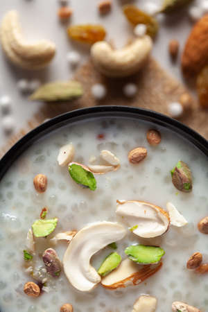 Close-up of Creamy Sabudana Kheer Garnished with dry fruits. Indian delicious dessert. Served in a black bowl. Top View on white background. jute matの写真素材