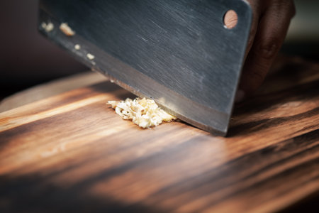 Close-up of chopped or minced fresh ginger (Zingiber officinale) on a wooden cutting board  with a chef knife.の写真素材