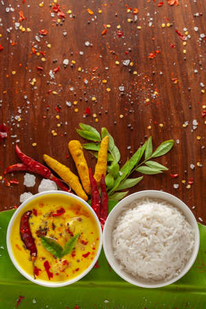 Close-up of Indian cooked rice with kadi or kadhi over the banana fresh green leaf. Garnished with curry-patta leaves and red chilli paper and salt.の写真素材
