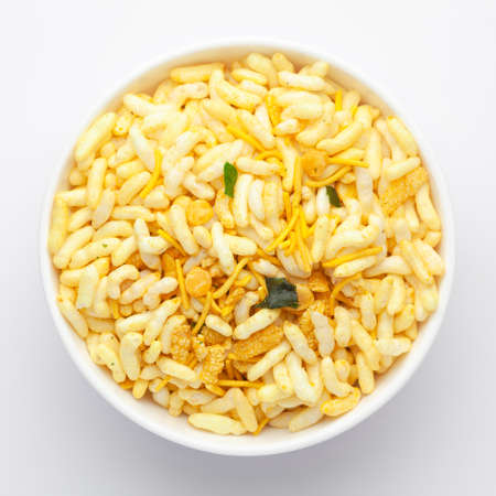 Close-Up of Crunchy Murmura in a white Ceramic bowl, made with Puffed Rice and Curry leaves. Indian spicy snacks (Namkeen), Top Viewの写真素材