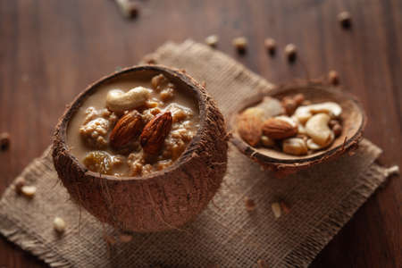 Close up of a famous Bengali dessert "Nolen Gurer Chanar Payesh" or Milk pudding of cottage cheese in Coconut shell. Top-down view, wooden background.の写真素材