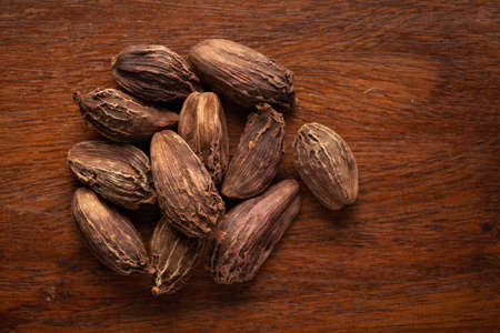 Macro close-up of Organic Black cardamom (Amomum subulatum)  on wooden top background. Pile of...
