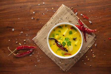 close-up of healthy curry of yogurt and potato (Dahi Aloo or Aaloo ) an Indian Classical dish. Served in Black bowl. Over Wooden Background and jute mat. Top viewの写真素材