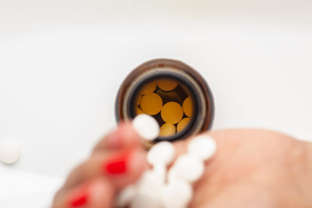 medicinal or herbal pill, capsule, and tablet are poured into an amber glass bottle by a female hand.の写真素材