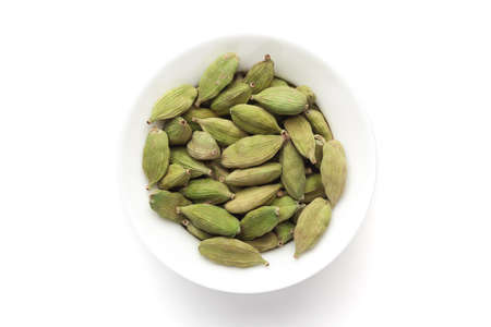 Macro close-up of Organic Cardamom or cardamum (Elettaria cardamomum) on white background. Pile of Indian Aromatic Spice. Top view