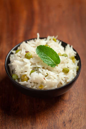 Close-up of Indian Basmati steamed Rice or matar (Pea) pulao or Pulav garnished with fresh green...