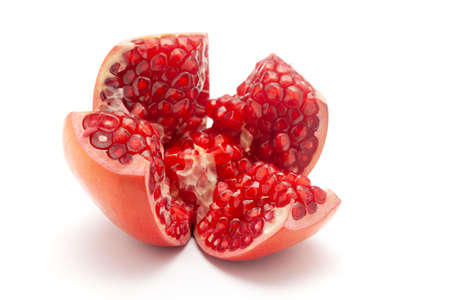 Close-up of  organic red pomegranate in section cut of four pieces  (Punica granatum) isolated over  background.の写真素材
